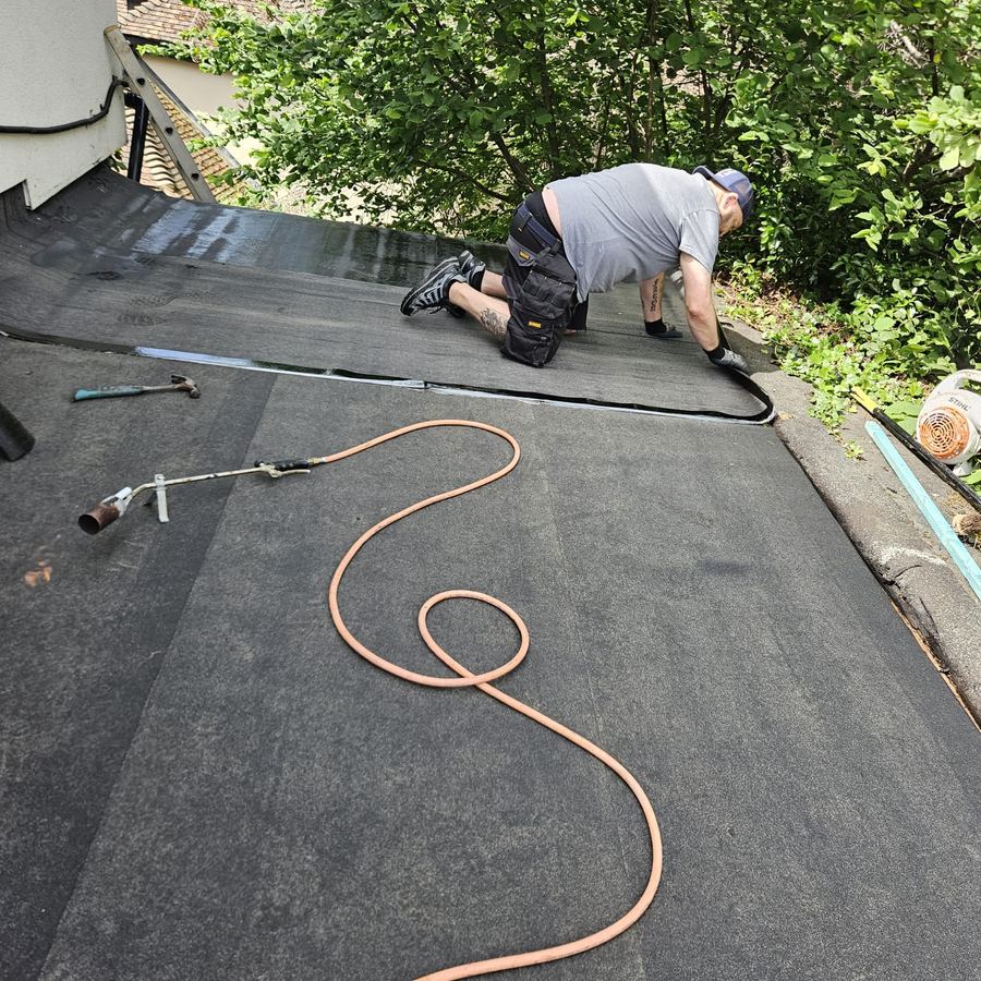 Roofer applying torch-on felt to a flat roof